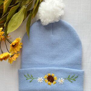 Blue Knit Beanie, Hand embroidered with a Sunflower Design and White Pom Pom.